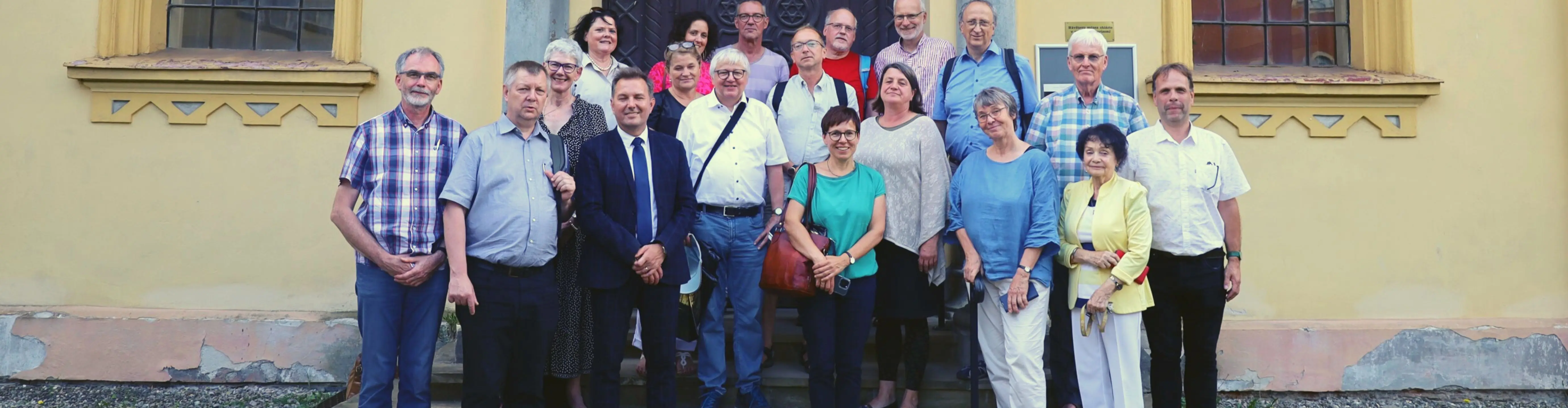 Ein Gruppenfoto im Sommer mit 17 Personen vor einem historischen Gebäude.