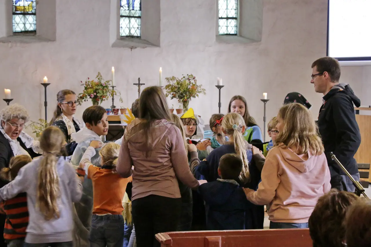 Kinder stehen im Kreis in einem Kirchenraum. 